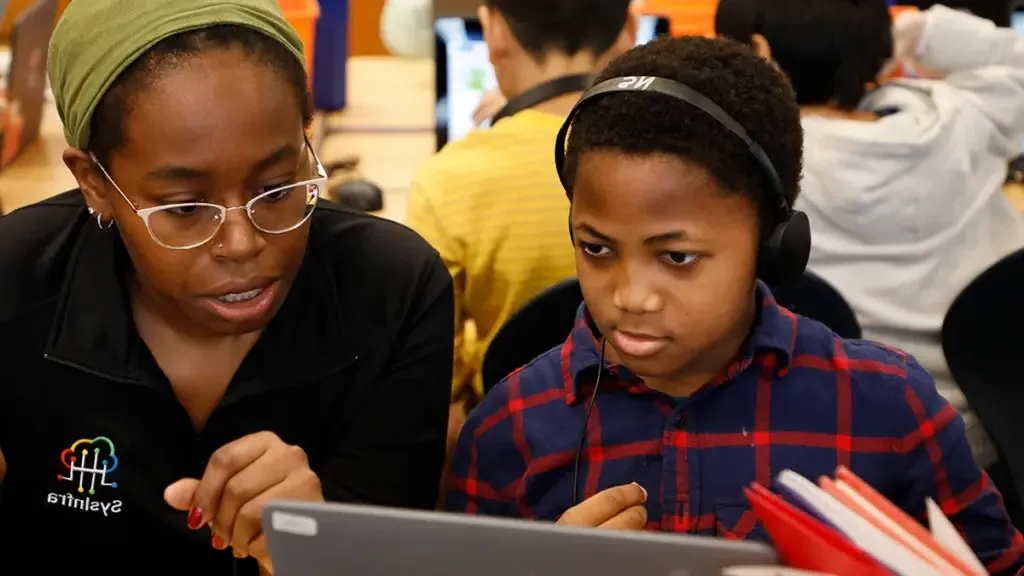 小学 school student sits with volunteer during week of code to complete coding activity